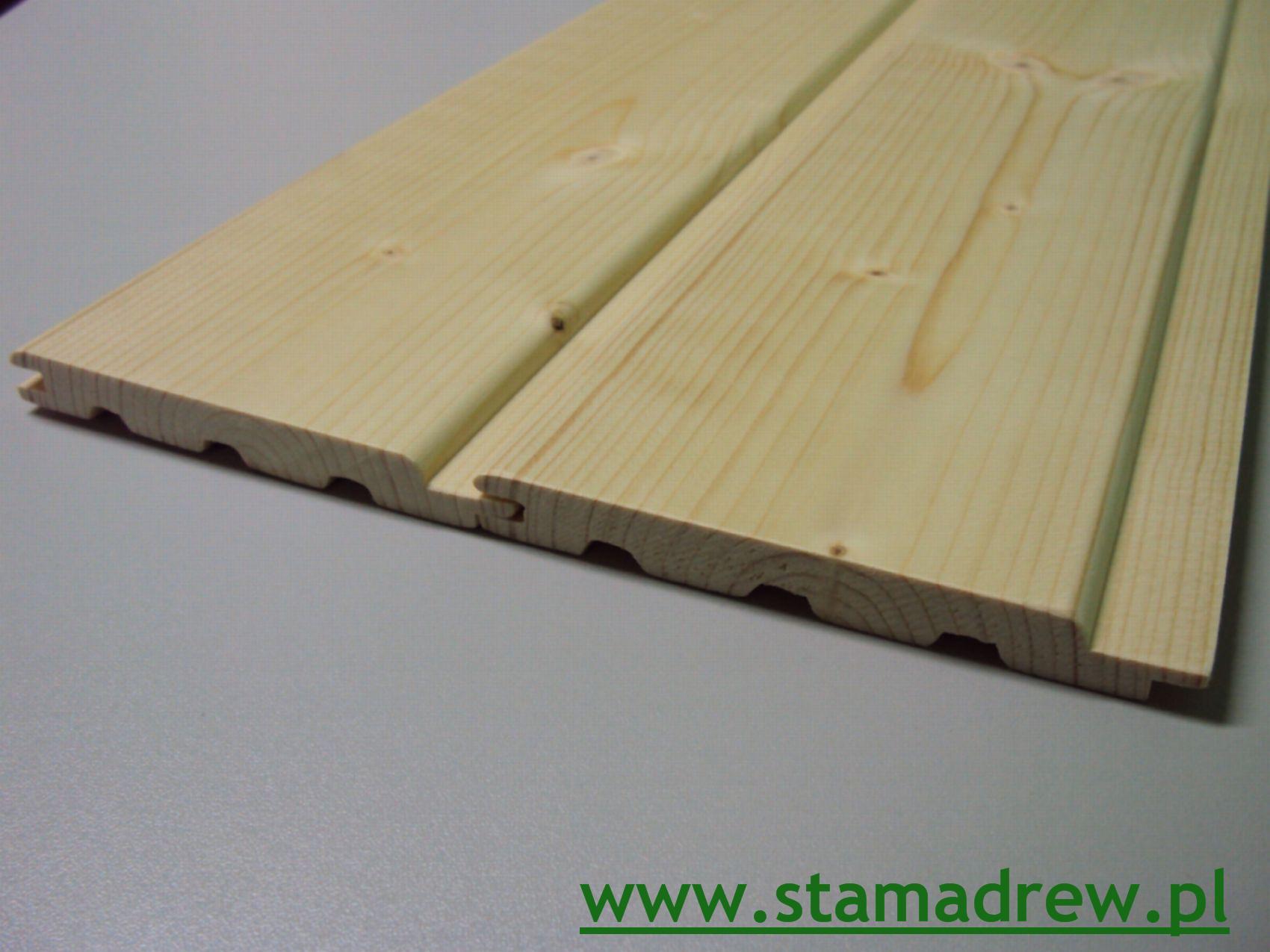 Dwa panele boazerii sosnowej z widocznym profilem łączenia pióro-wpust, leżące na szarej powierzchni. Widoczne sęki i usłojenie drewna.